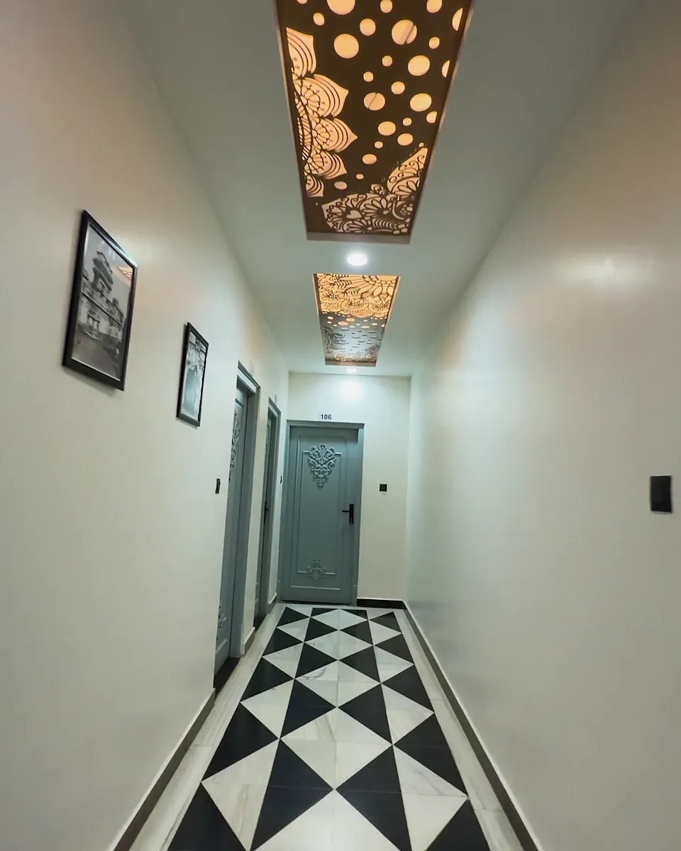 Hotel corridor with carved jaali ceiling and checkered marble floor