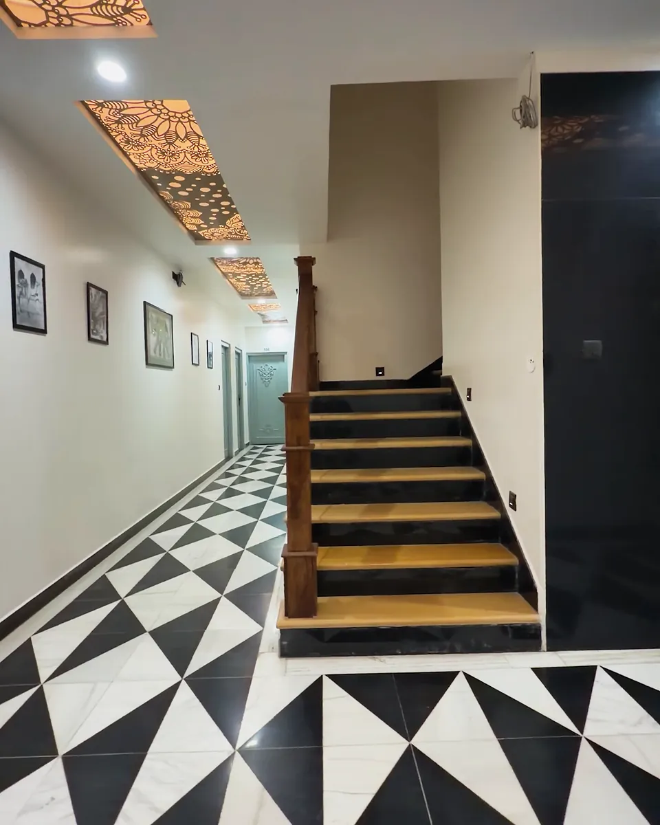 Checkered marble floor and staircase under a carved jaali ceiling